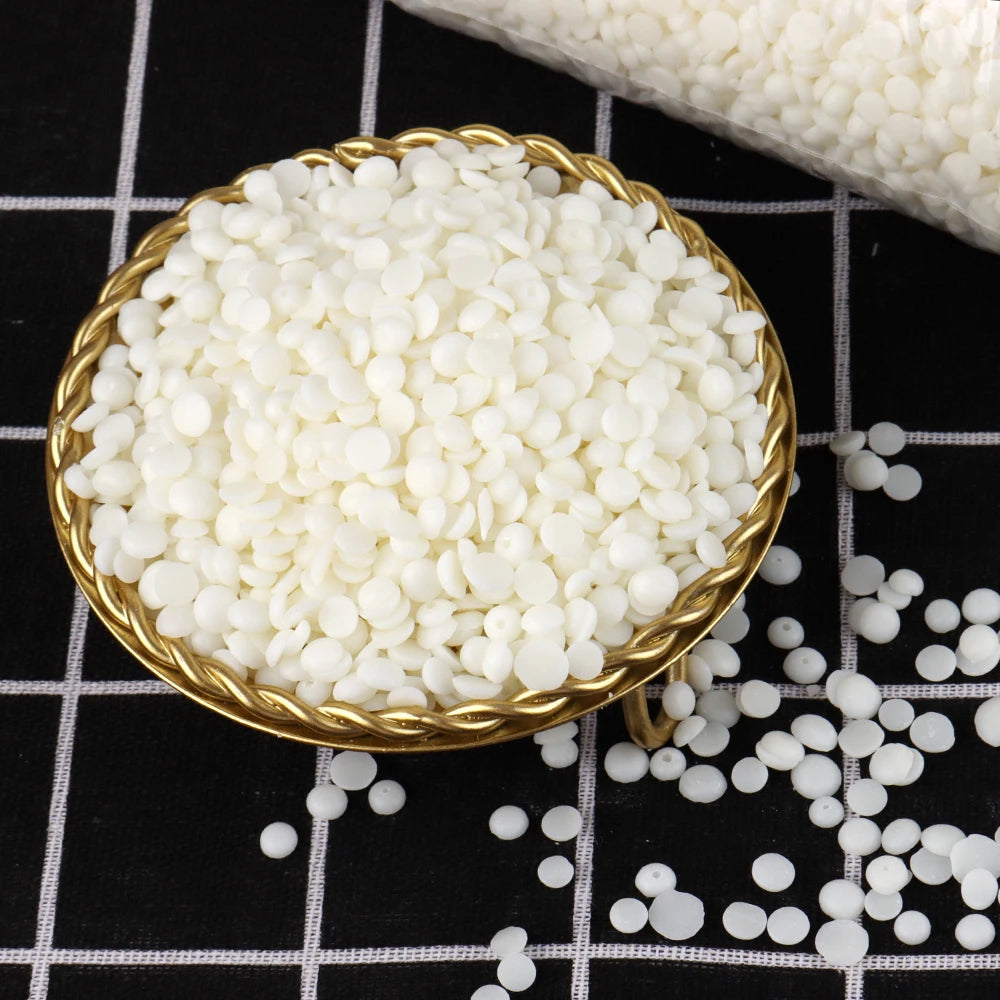 A golden bowl filled with white soy wax granules, set against a black and white checkered background.