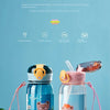 A clear glass water bottle with a pink lid and straw, featuring a cute bear design, set against a light blue background.