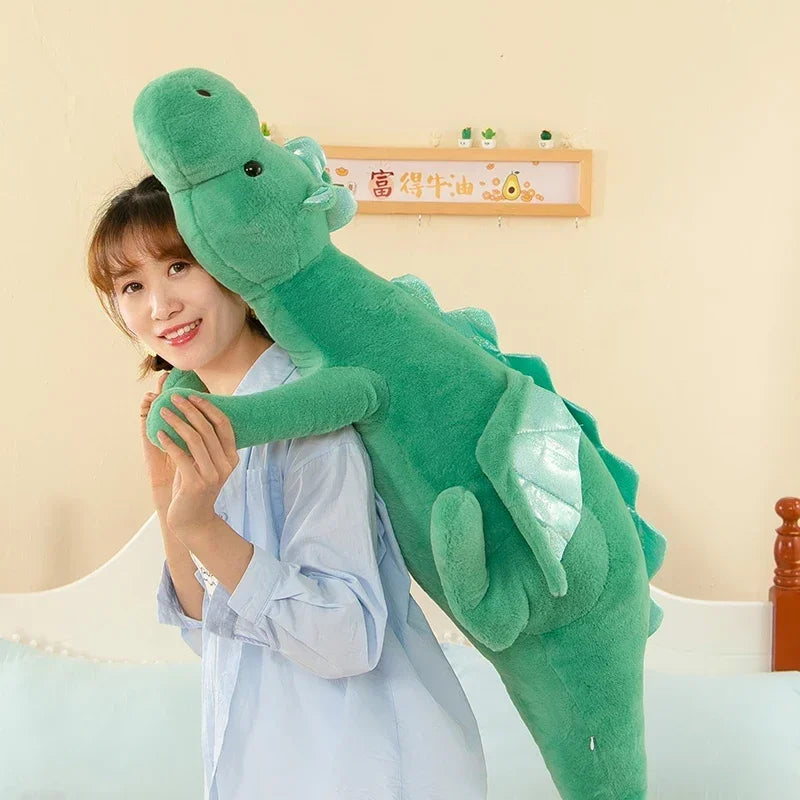 A woman is holding a large, green dragon plush toy against her chest.