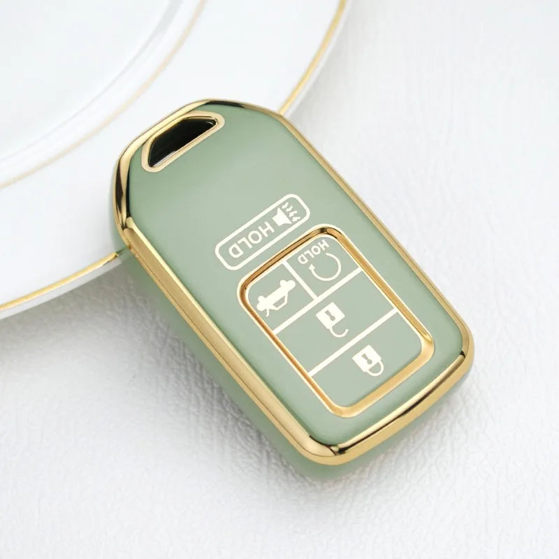 A light green TPU protective key case with gold accents resting on a white surface.
