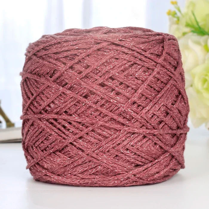 A ball of metallic pink silk crochet yarn with silver shimmer thread for knitting and macrame.