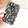A black and white patterned card holder featuring a hand-drawn spade flower design resting on a white surface.