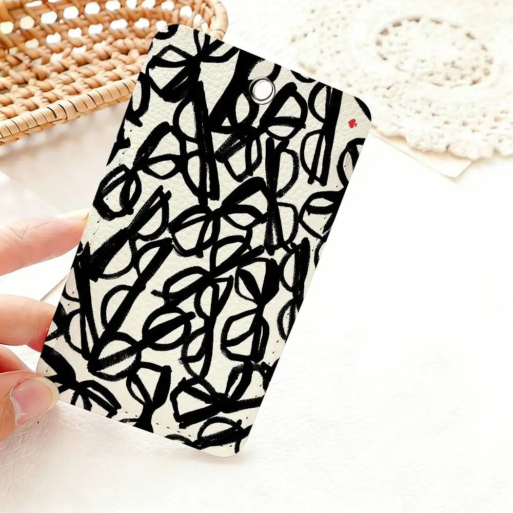 A black and white patterned card holder featuring a hand-drawn spade flower design resting on a white surface.