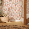 A close-up of vintage floral peel-and-stick wallpaper on a wall with natural light and wooden flooring.