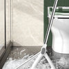 A silver squeegee broom is shown cleaning a floor near a toilet bowl.