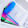 A transparent A4 binder with six colored pockets and a white sheet inside, next to a keyboard.