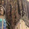 Black gothic lace curtain valance with silver trim and pendant tassels hanging in a window.