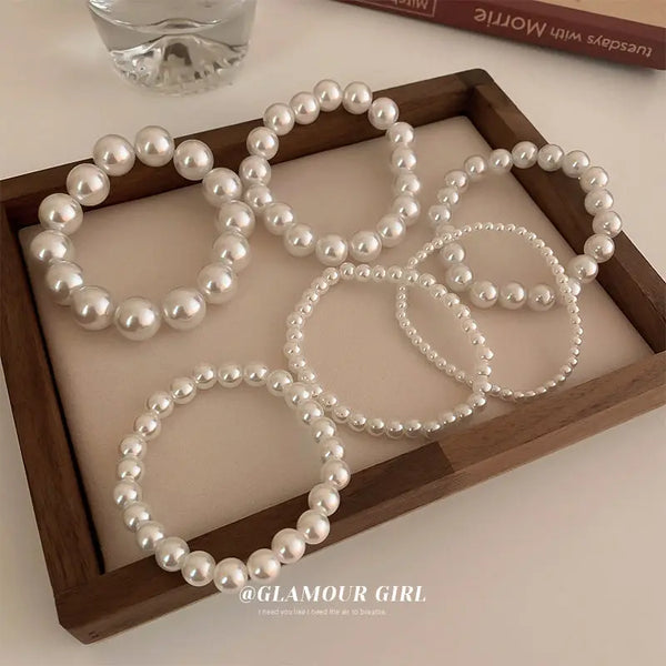 Eine Sammlung eleganter Perlenarmbänder mit Glitzer, präsentiert in einer Holzschale.
