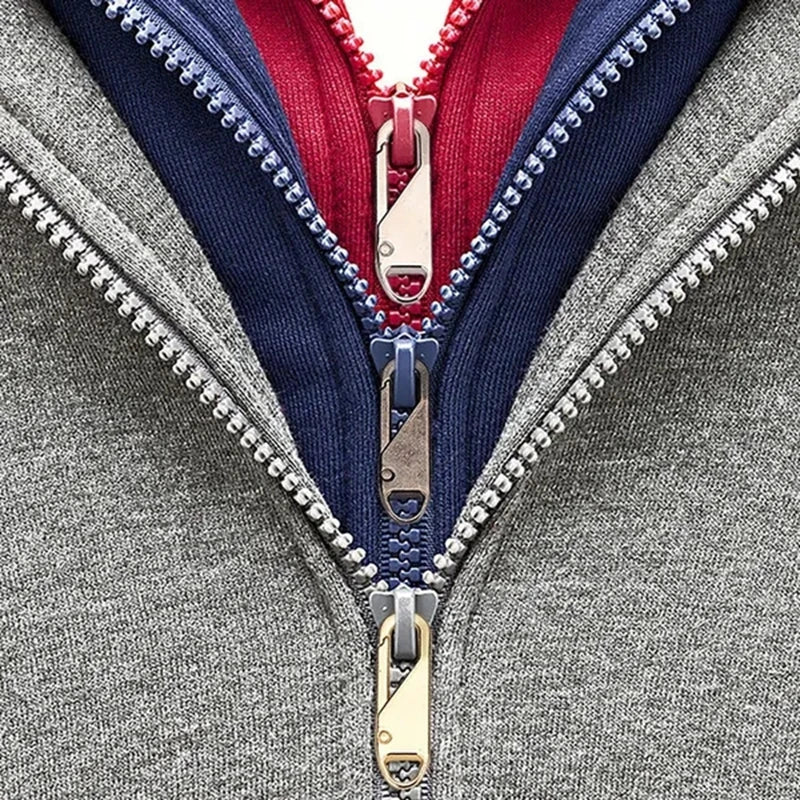 Close-up of a gray jacket featuring three colored zippers: navy, red, and gold.