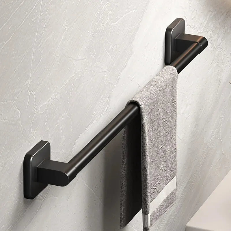 A black wall-mounted towel rack holding a gray towel on a light-colored wall.