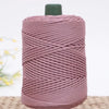 A spool of pink crochet ice rope with a green cap resting on a woven mat.