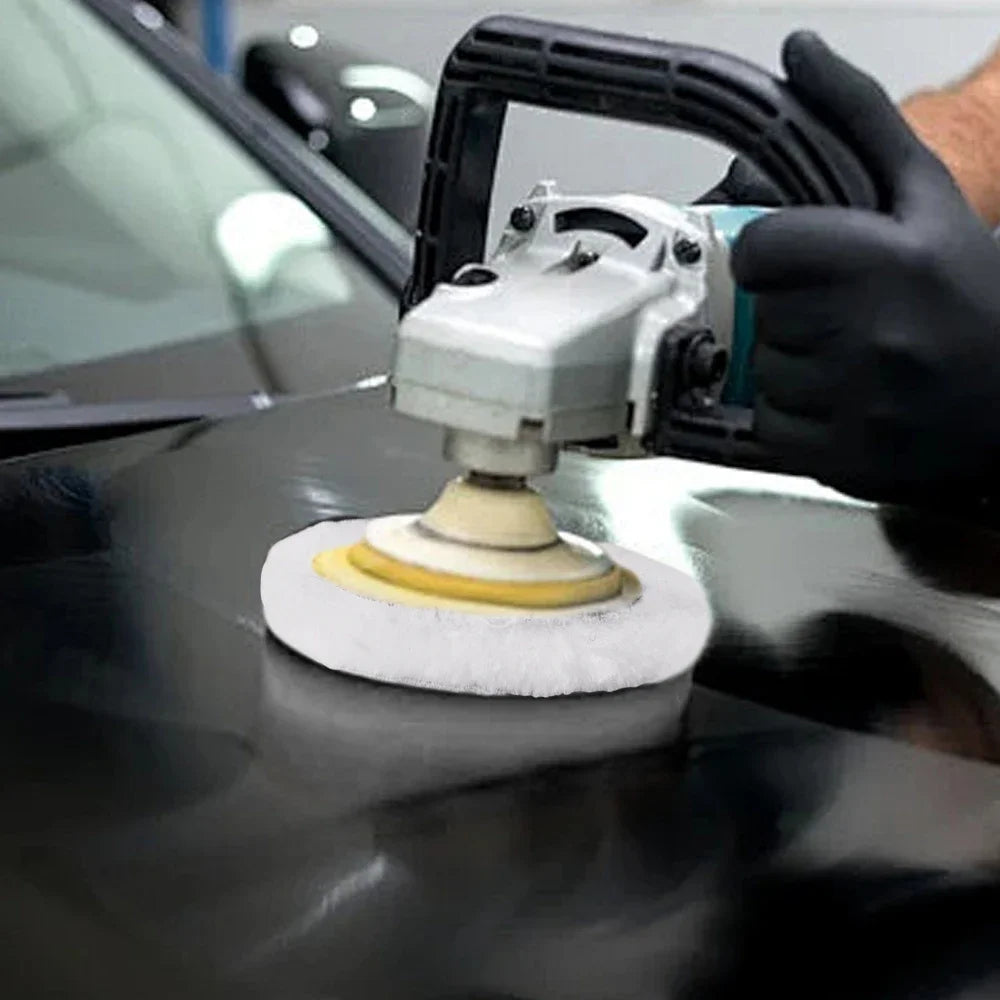 A hand is using a polishing tool with a wool disc on a dark car surface.