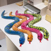 A collection of nine lifelike snake plush toys in various colors and patterns laid out on a white surface.