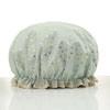 A light mint green reusable elastic shower cap decorated with gold heart patterns.