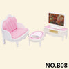 A miniature dollhouse furniture set featuring a pink tufted armchair, a pink stool, and a white table with a monitor.