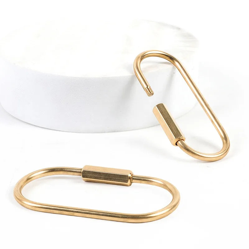 A set of ten gold brass keychain charms with locking carabiner clips displayed on a white background.