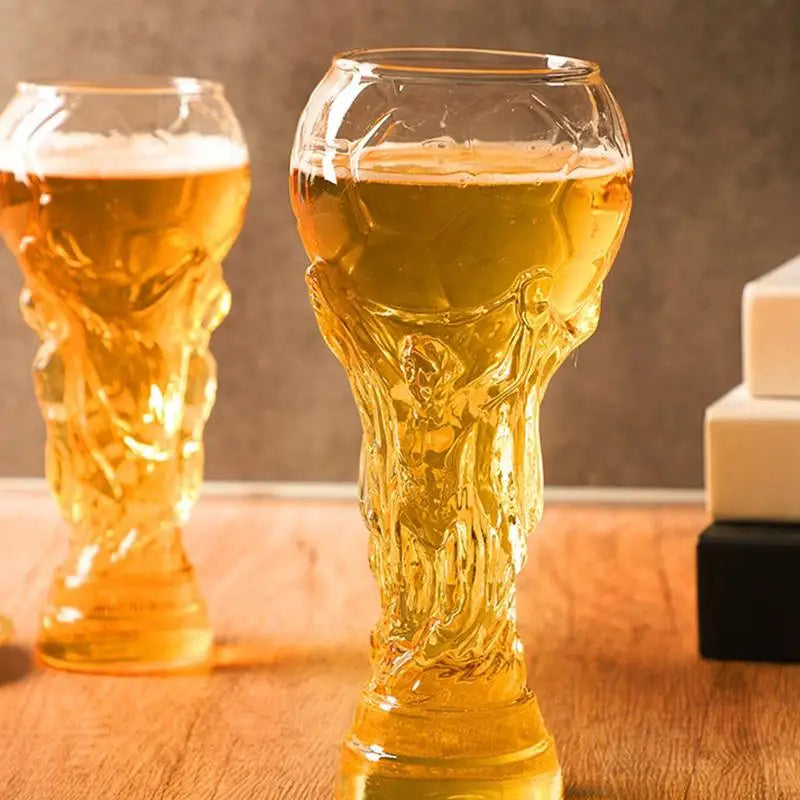 Goldfarbener Trophäen-Glas gefüllt mit Bier steht auf einer Holzoberfläche.