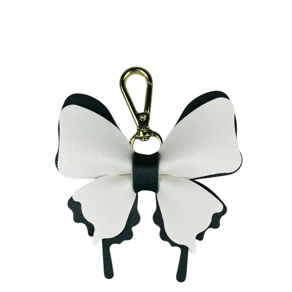 A white and black PU leather butterfly bag charm with a gold-colored keyring.