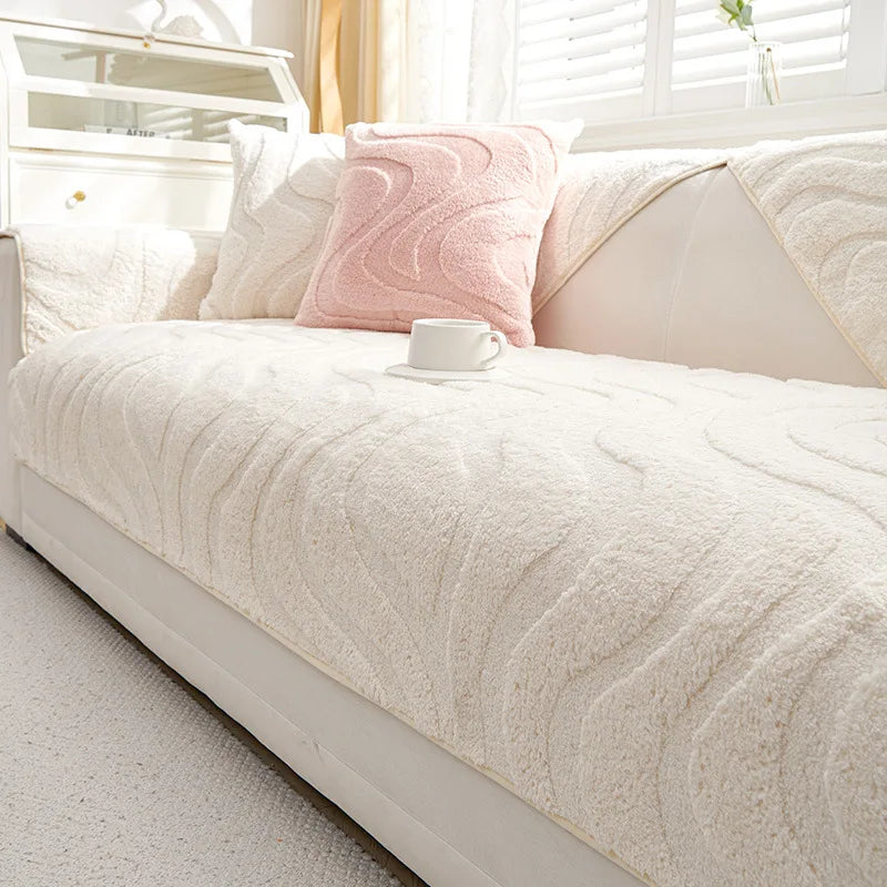 Funda de cojín de sofá texturizada en crema con un cojín decorativo rosa sobre una cama blanca.