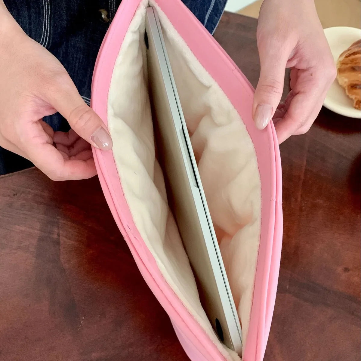 Person hält rosa gesteppte gepolsterte Laptoptasche mit geöffnetem Reißverschluss, Innenansicht.