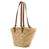 A handwoven straw tote bag with brown leather straps.