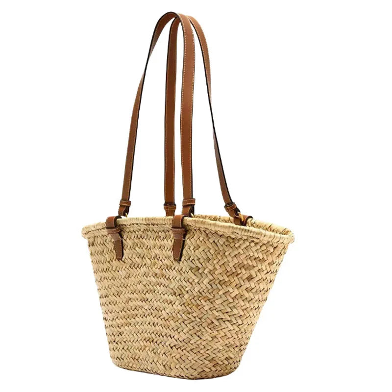 A handwoven straw tote bag with brown leather straps.