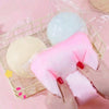 Hände halten eine große rosa Squishy-Fidget-Kugel und eine hellblaue Squishy in einer klaren Tasche auf einem geflochtenen Ta