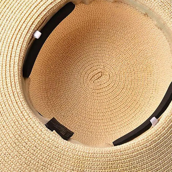 Primer plano de un sombrero tejido beige con inserciones negras y un ajuste blanco visible dentro de la copa.