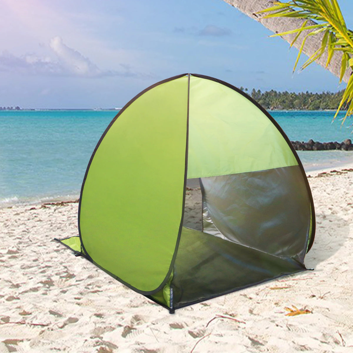 A lime green instant pop-up beach tent with a black frame set up on a sandy beach near the ocean.