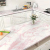 A kitchen countertop featuring pink marble with white veining, displaying cabinets and a sink.