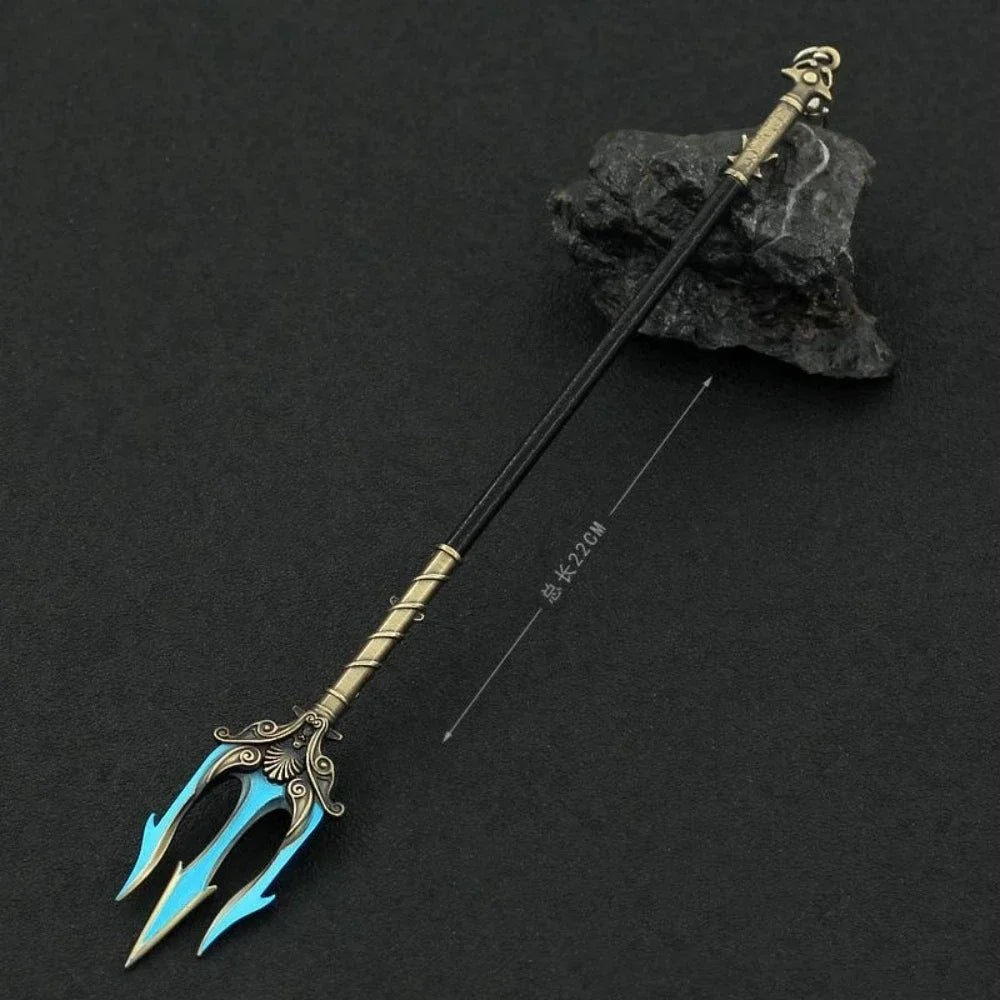 A detailed metal sword keychain featuring a stylized blue blade and gold hilt, resting on a dark rock.