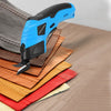 A blue cordless electric scissor tool is shown cutting fabric and leather materials on a wooden surface.