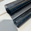 A close-up view of a dark gray ceramic car window tint film rolled out, showing its layered, reflective surface.