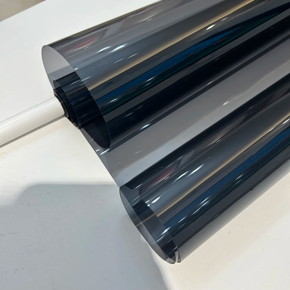 A close-up view of a dark gray ceramic car window tint film rolled out, showing its layered, reflective surface.