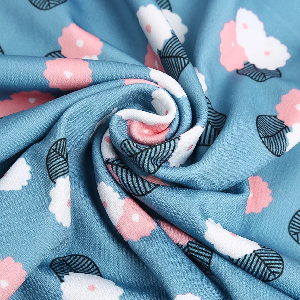 Blue fabric with a pink floral pattern is tightly rolled, showing the stretchable suitcase protector cover.