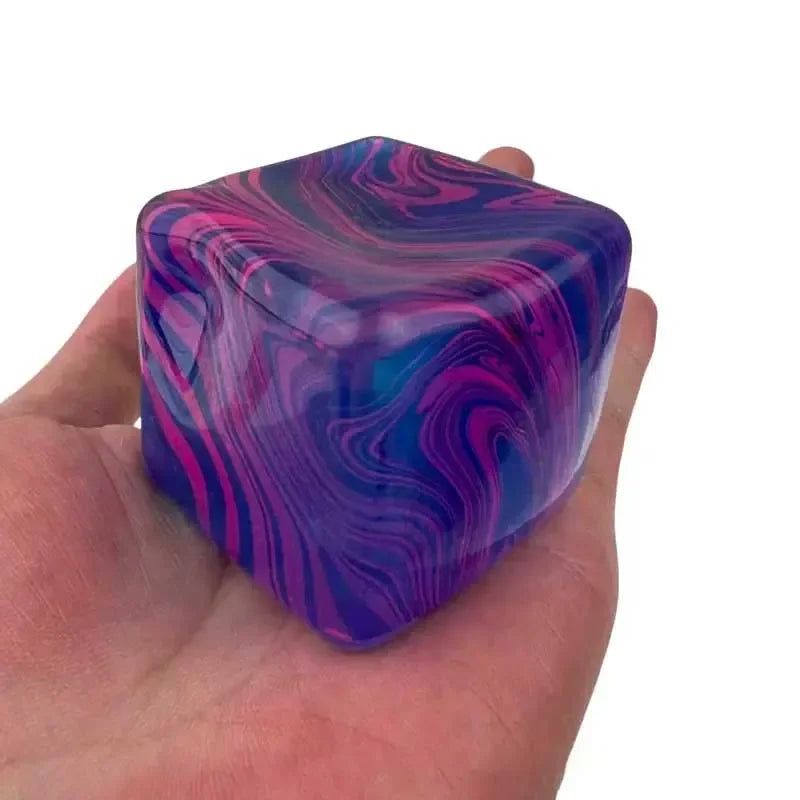 Une main tient un cube de jeu en gel apaisant, translucide, tourbillonnant, violet et rose.