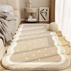 A plush, light beige decorative area rug with subtle geometric patterns and white borders placed on a wooden floor.