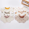 A collection of light-colored muslin cotton baby bibs and burp cloths with various patterns and snap closures.