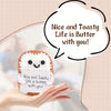 A handcrafted crocheted plush ornament shaped like a smiling egg is held in a hand with a speech bubble saying Nice and Toast