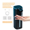 A hand is interacting with a dark teal touchless automatic soap dispenser bottle.