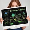 A young girl holds a digital drawing tablet displaying colorful alien and space doodles on a black screen.