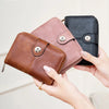 A hand holds a brown leather wallet and a black leather wallet, demonstrating RFID protection.