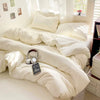 A white cotton bedding set featuring a flat sheet, duvet cover, and pillowcases displayed on a bed.