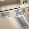 Three rectangular floor mats with the word HOME printed on them are placed in front of a modern toilet.