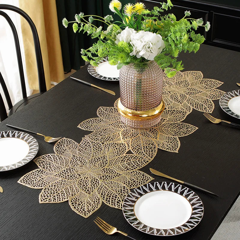 A set of ornate gold leaf floral PVC table runners and placemats displayed on a black table.