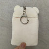 A white Rilakkuma plush toy with a silver keychain attached to its ear.