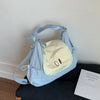 Light blue nylon messenger bag with a light yellow patch and brown embroidered eyes