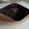 A close-up of a beige crocodile-embossed PU leather envelope clutch with a gold zipper and interior lining.