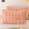 A fluffy, light pink quilted velvet pillow is displayed on a white surface.