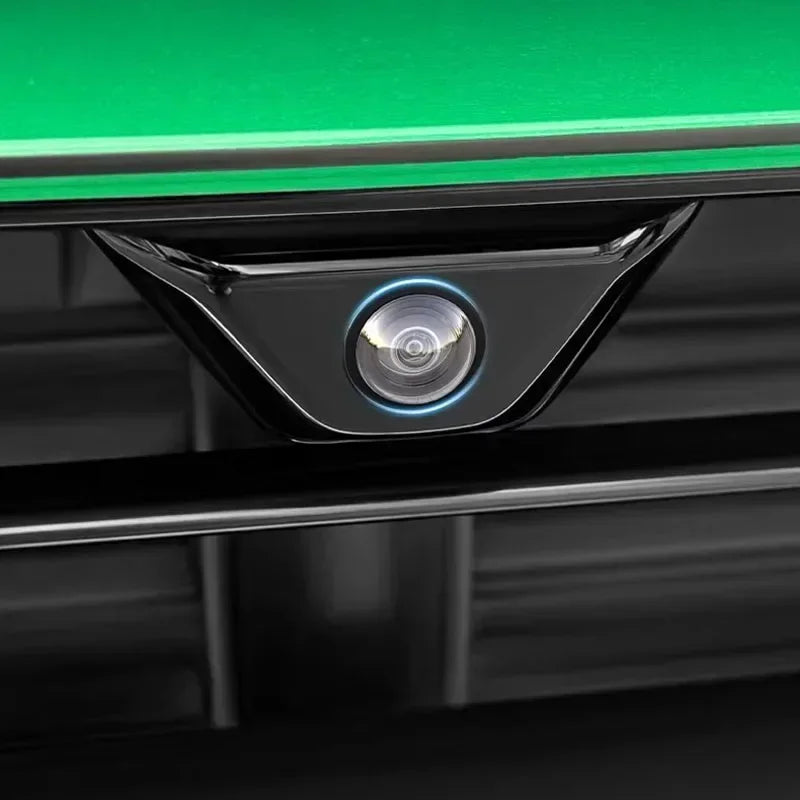 A close-up view of a black camera housing with a silver lens and blue light, mounted on a green surface.